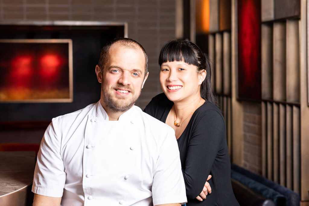 Man in chef whites and woman in black top sitting in a restaurant