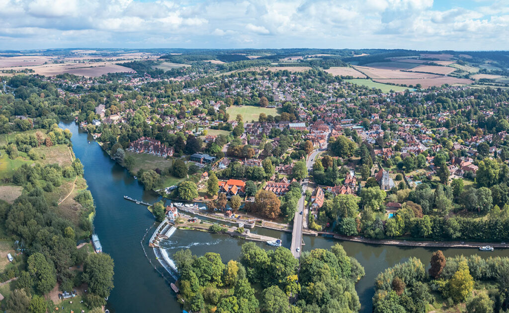 Aerial view of river with weir and boats, villages and fields in Goring and Streatley, England